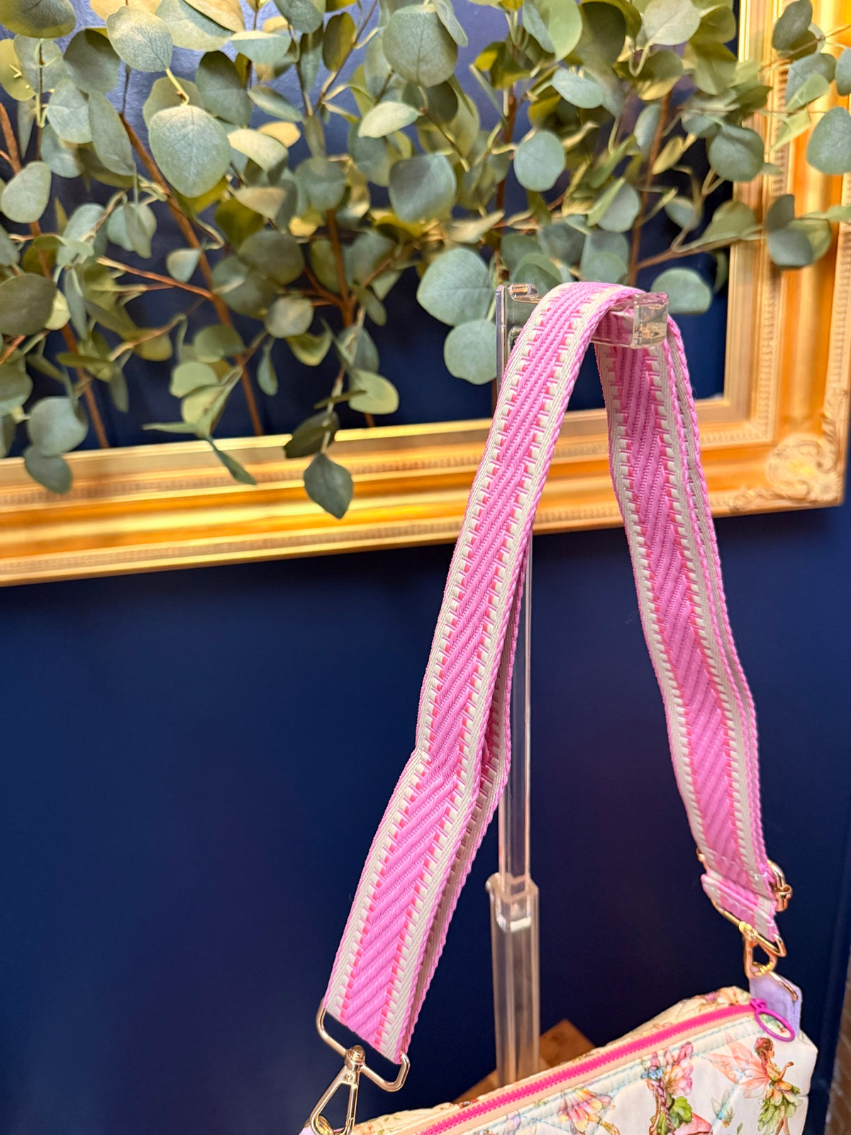 Close-up of pink woven adjustable crossbody strap with gold hardware