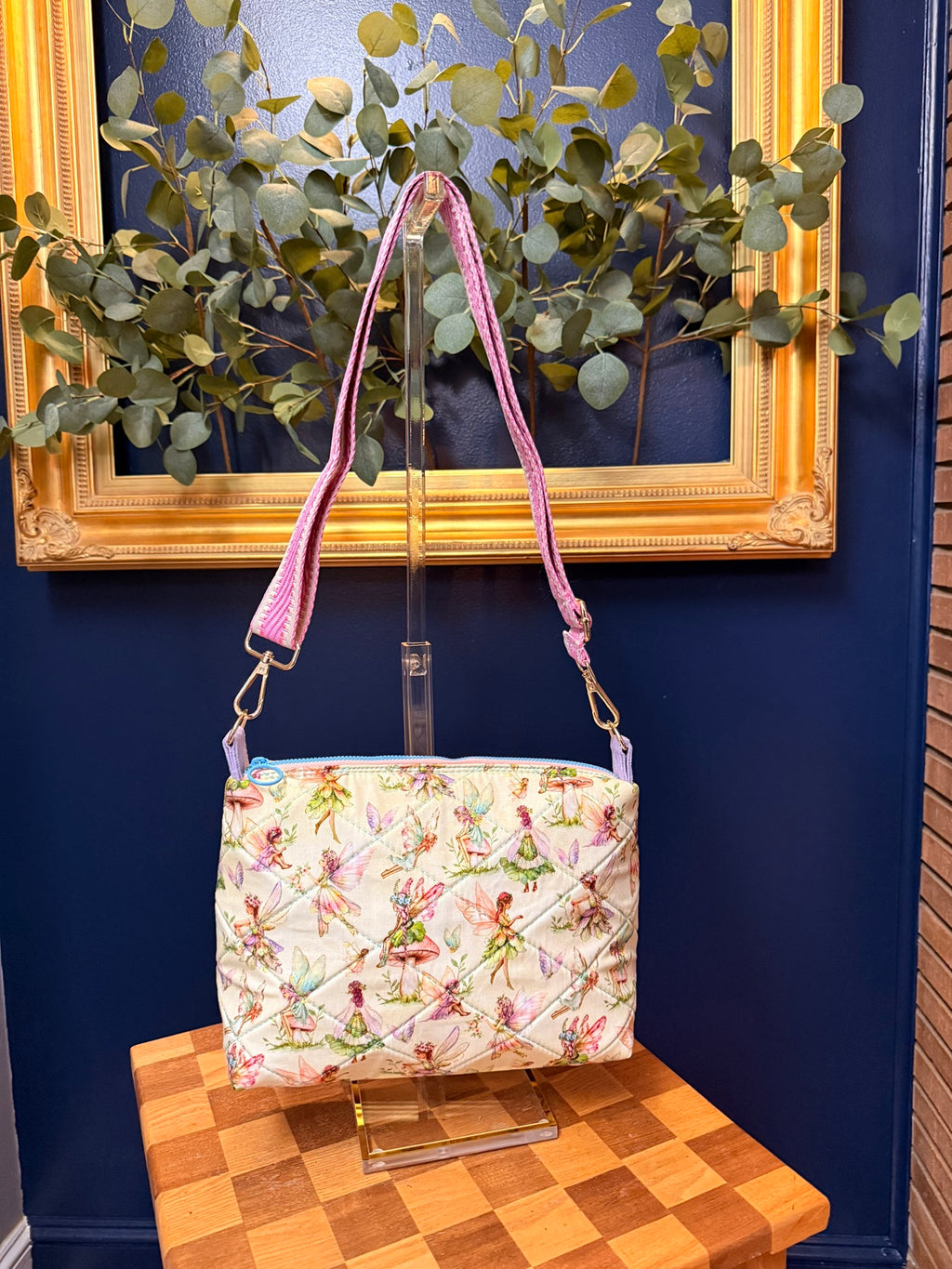 Quilted crossbody bag in storybook fairy print with blue zipper and pink woven strap