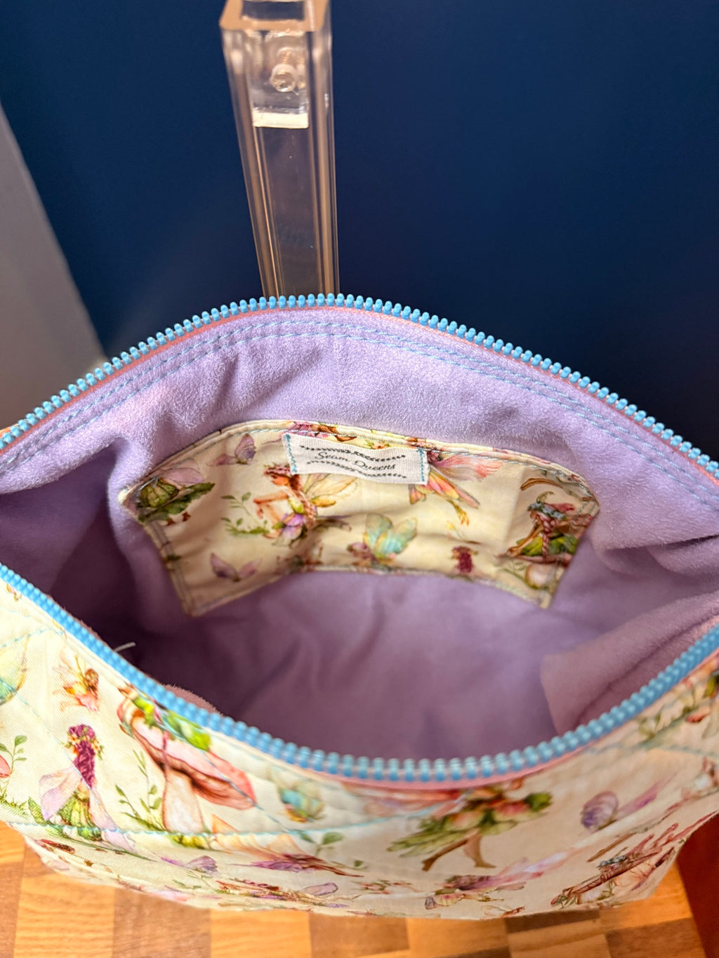 Interior of quilted crossbody showing purple suede liner and blue zipper