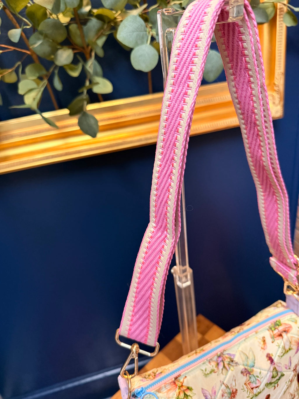 Close-up of pink woven adjustable crossbody strap with gold hardware