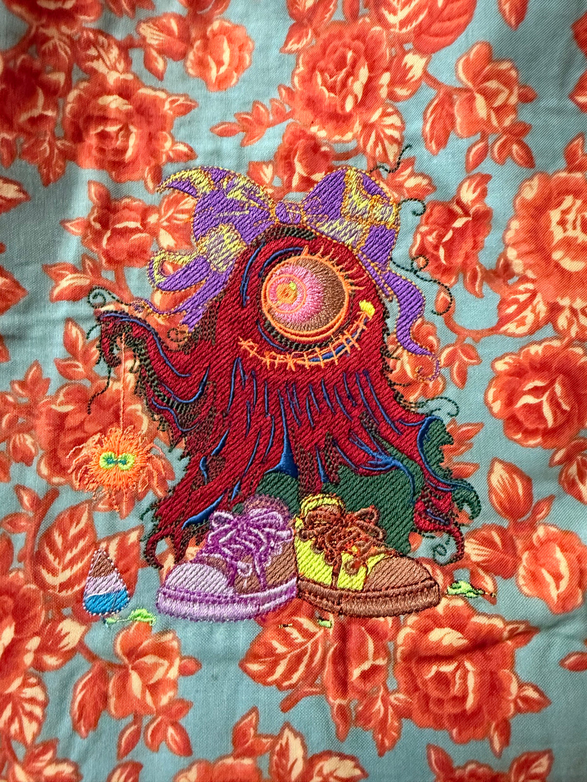 Close-up of the embroidered little monster with bow and mismatched shoes