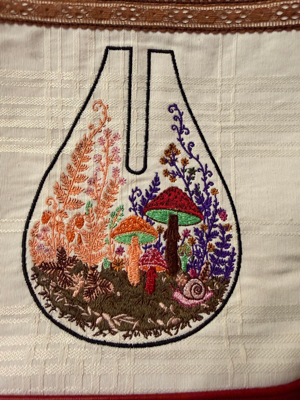Close-up of the embroidered mushroom terrarium with ferns and a tiny snail