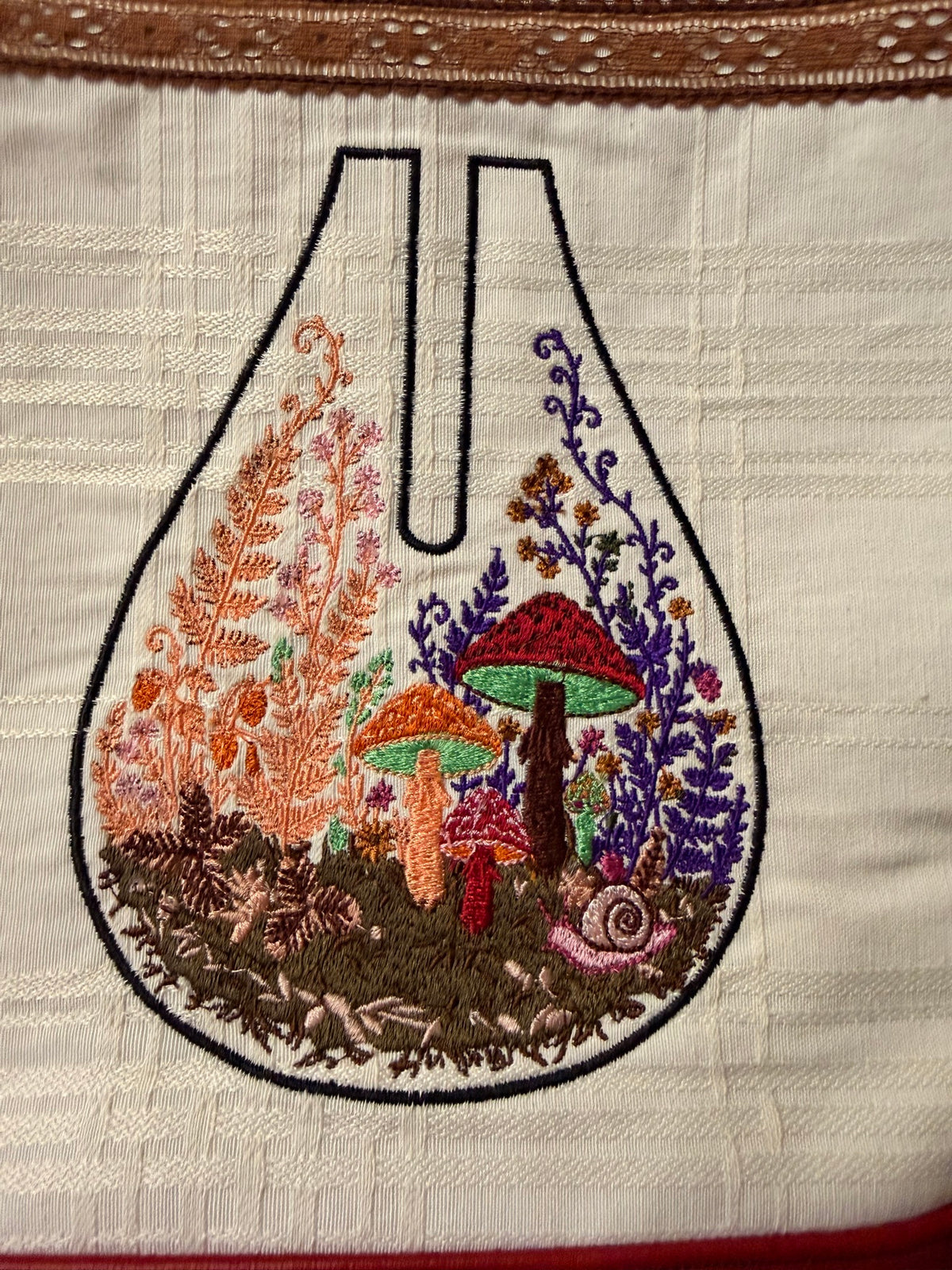 Close-up of the embroidered mushroom terrarium with ferns and a tiny snail