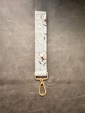 Keychain wristlet in gray fabric with rust floral print and gold hardware