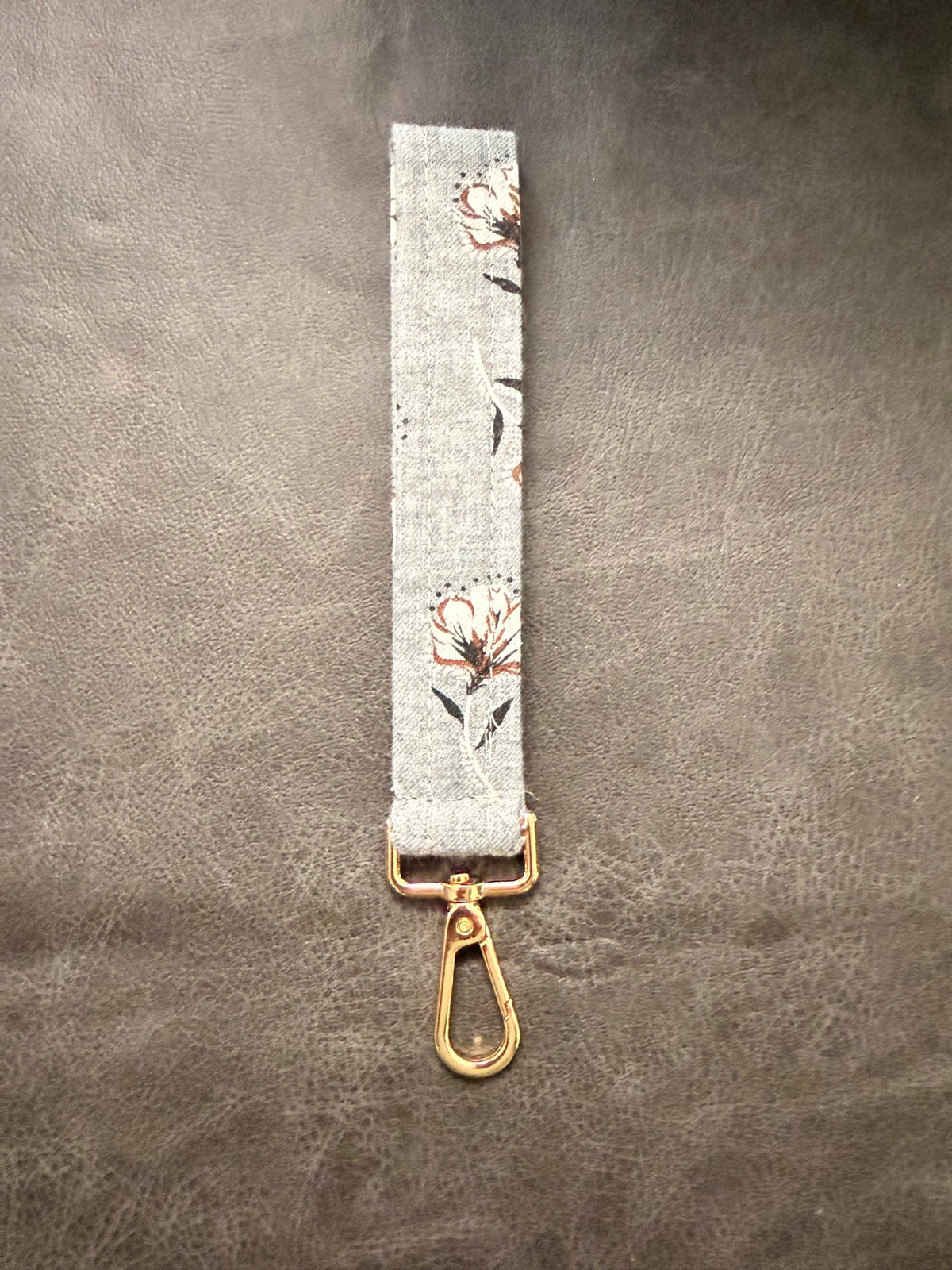 Keychain wristlet in gray fabric with rust floral print and gold hardware